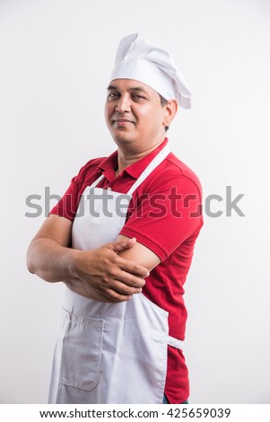 Portrait of handsome Indian/Asian male chef in uniform presenting something, standing isolated over white background