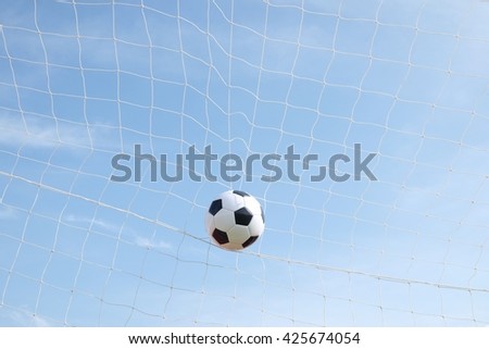 soccer ball in goal net with blue sky