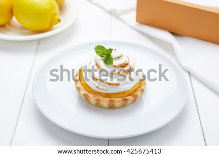 Lemon tart with whipped cream and mint sweet dessert on white plate
