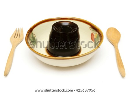black jelly, grass jelly or leaf jelly, Chinese dessert, in a bowl with wooden spoon and fork isolated on white background