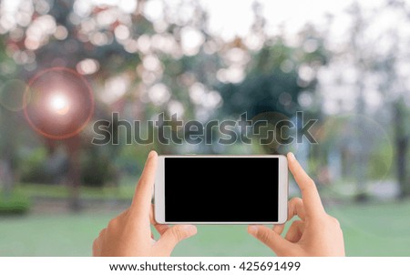 woman use mobile phone and blurred image of the park in evening time