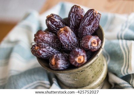 dried dates in a copper bowl on a blue plaid tablecloth