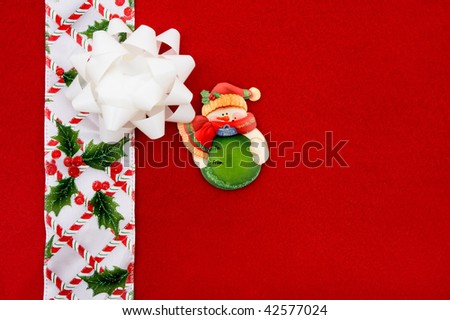 A white bow with a candy cane and holly ribbon on a red background, christmas border