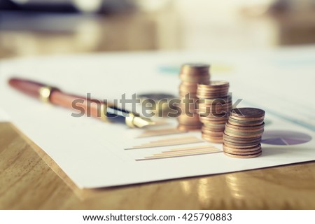 Saving stack coins money concept,graph,chart  document and pen on desktop desk in hipster office,copy space.selective focus,vintage color Royalty-Free Stock Photo #425790883