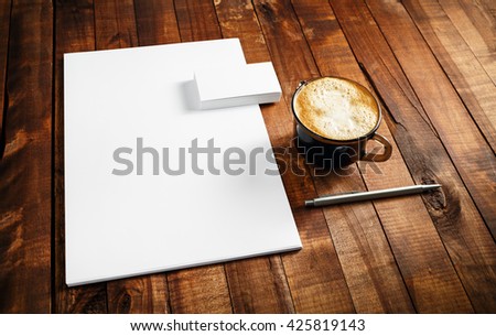 Photo of blank stationery set. Corporate identity template on vintage wooden table background. Letterhead, business cards, coffee cup and pen.