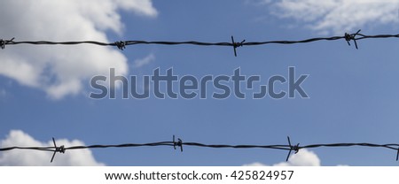 Barbed wire on the background of the cloudy sky.