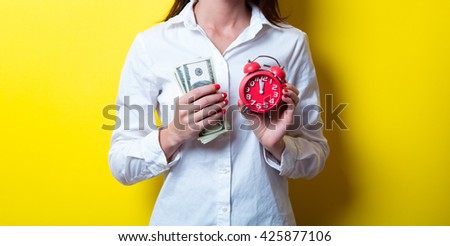 photo of beautiful young woman with clock and money on the yellow background