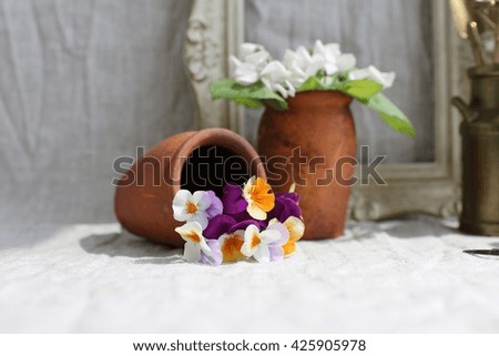 Fresh small bouquet of pansies in a clay very old pot, white violets, vintage wooden golden frame, natural grey linen background, light, sunny day