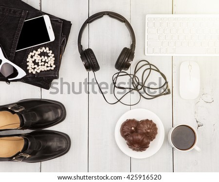 Travel concept - shoes, jeans, smartphone, headphones, computer keyboard, sunglasses and coffee on white wooden desk
