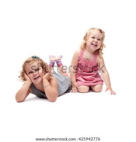 Couple of young little girls sinsters with curly hair in gray and pink dress lying over isolated white background