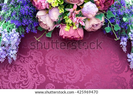 Artificial flower bouquet on a crimson table cloth background