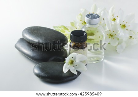 aroma oils and white flower on black stone