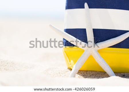 closeup picture of colorful beach bag and starfish at the beach, vacation concept