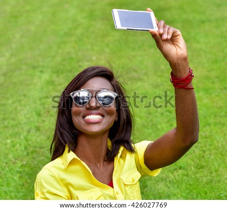 Beautiful smiling african girl taking selfie.  Fashion woman in sunglasses outdoor. Healthy Smiling Girl in Green Grass.