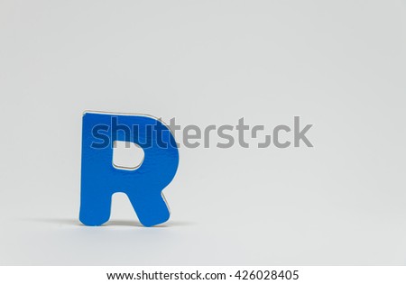 Blue wooden alphabet R with white background and selective focus