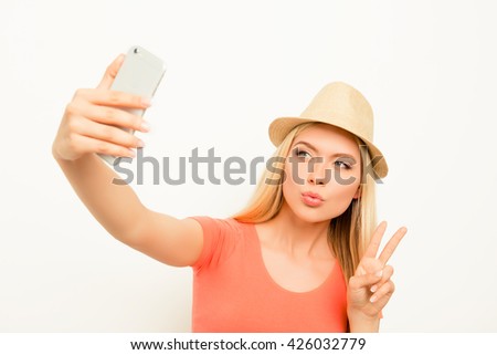 Woman in hat making selfie, pouting  and showing two fingers