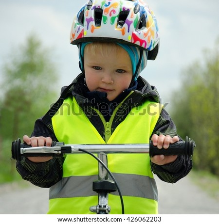 Happy boy learns to ride a bike on a bike trail in the nature. He has a helmet because of safety. Child concept.