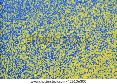 The walls are painted   yellow blue white old paint. The bright colored textured background. Macro photo. Paint splashes