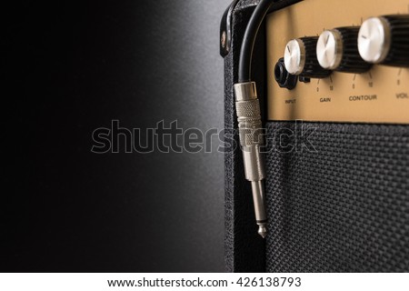 Black guitar amplifier with jack cable on black  background Royalty-Free Stock Photo #426138793