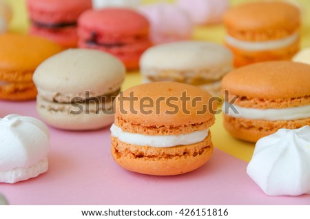 Assortment of macarons and meringues on pink background