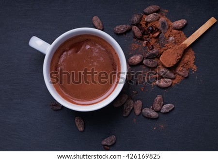 Hot chocolate in a cup on the black background, top view. Dark styled photo.