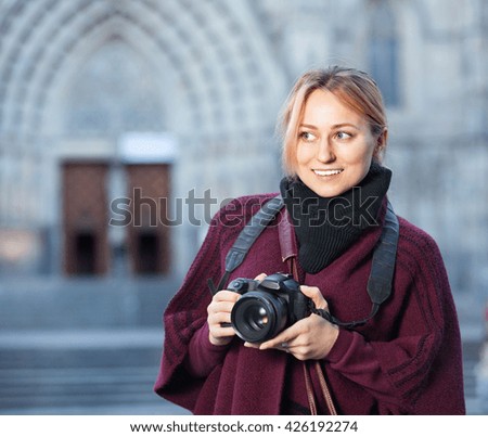 Young pleasant woman looking curious and taking pictures outdoors