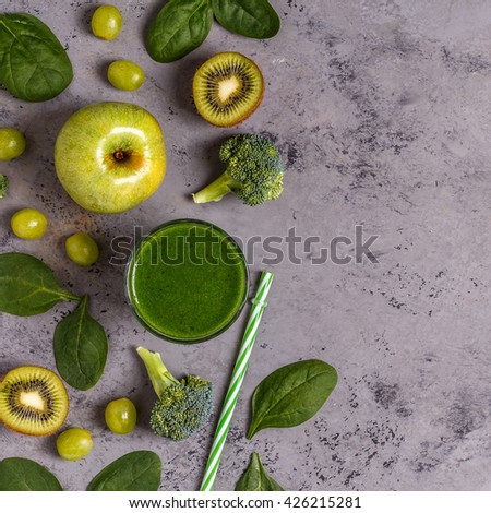 Green smoothie with ingredients on  concrete surface, top view, copy space.