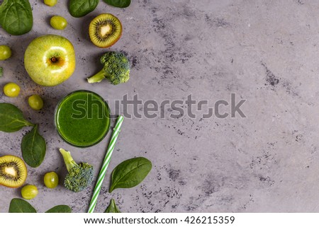 Green smoothie with ingredients on  concrete surface, top view, copy space.