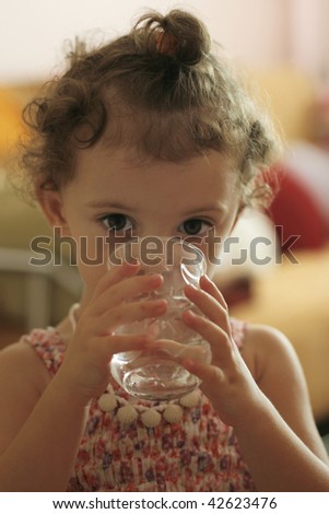 little girl drink water, focused at the camera with her big eyes