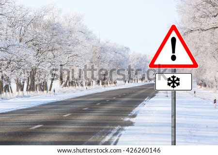 Empty winter road with sign warning snowfall