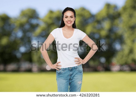 advertisement, clothing and people concept - happy smiling young woman or teenage girl in white t-shirt over summer park background