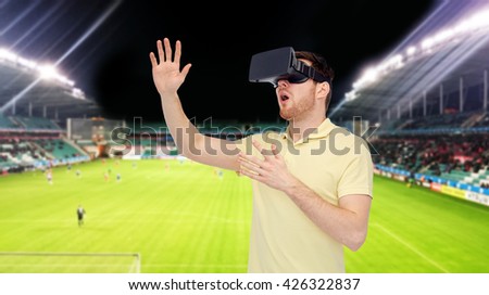 3d technology, virtual reality, sport, entertainment and people concept - happy young man with virtual reality headset or 3d glasses playing game over football field on stadium background