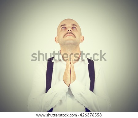 Bald man praying,imploring, hands clasped hoping of miracle isolated on background. 