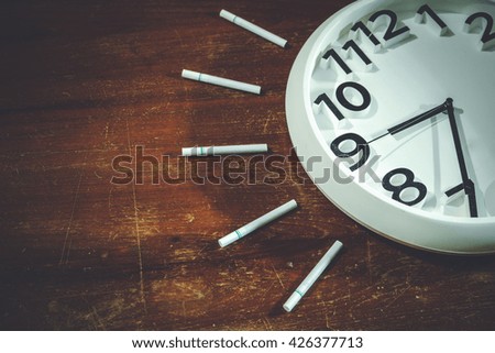 Cigarette and white watch on wooden background