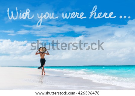 Wish you were here cloud message written in sky above woman walking on beach vacation Luxury travel Caribbean destination. Tourist relaxing on summer holiday at resort. Popular saying postcard. Royalty-Free Stock Photo #426396478