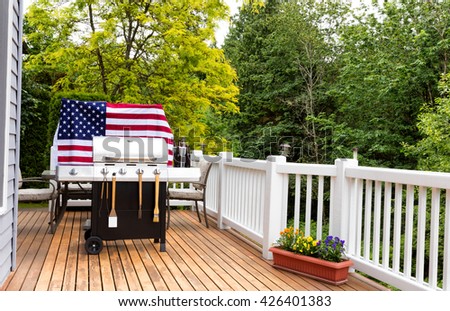 Home outdoor patio and barbecue cooker with bucket of cold bottled beer on ice with USA wooden flag in background. 