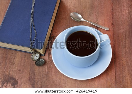Black coffee in a teal blue cup with a book and a vintage chain watch, on a dark wooden background with copyspace; 'Time to Read (or Study)' concept
