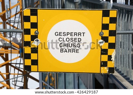 Yellow and black No Entry sign in 4 languages - gesperrt, closed, chiuso, barre - German, English, Italian, French.