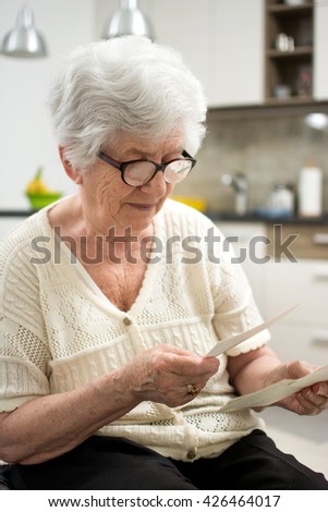 Grandma sitting at home and looking at old photos.