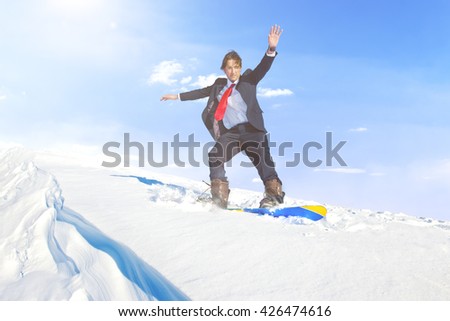 Businessman snowboarding on top of a mountain. 