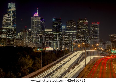 A long exposure of the Philadelphia skyline, with light trails from the freeway below