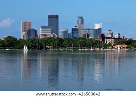 Downtown Minneapolis skyline reflecting in Lake Calhoun with sail boat.