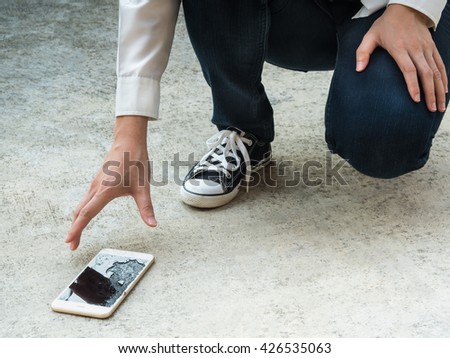 Person Picking Broken Smart Phone (Cracked Screen) of the Ground