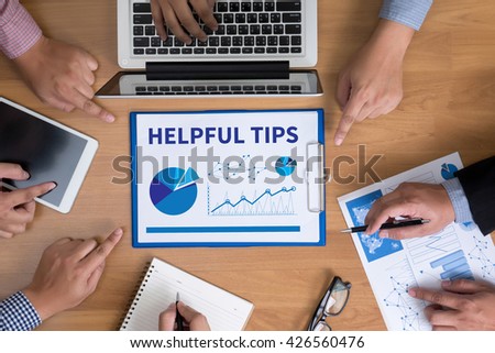 HELPFUL TIPS  Business team hands at work with financial reports and a laptop, top view