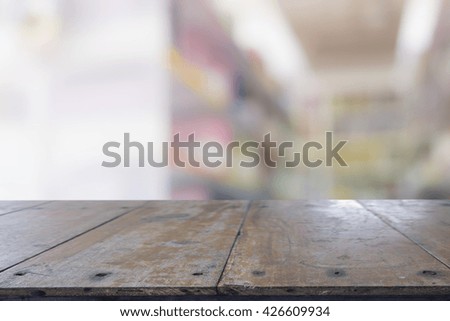 Empty wood table top ready for your product display montage. with book shelf in library blurred background.  Blurry perspective view of educational study room space with book shelves
