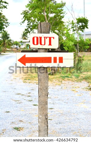 Out sign board with red arrow on the tree