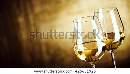 Banner of Two glasses of white wine standing side by side in a close up view over a panoramic abstract brown background with copy space Royalty-Free Stock Photo #426651925