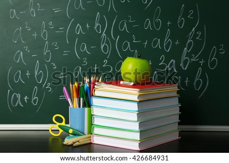 School books on desk near chalkboard