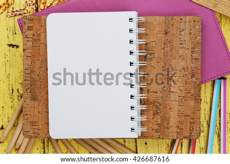 Office set with notebooks, colored pencils and pens on yellow wooden background