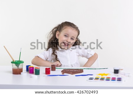 Cute little girl painting picture on a light background